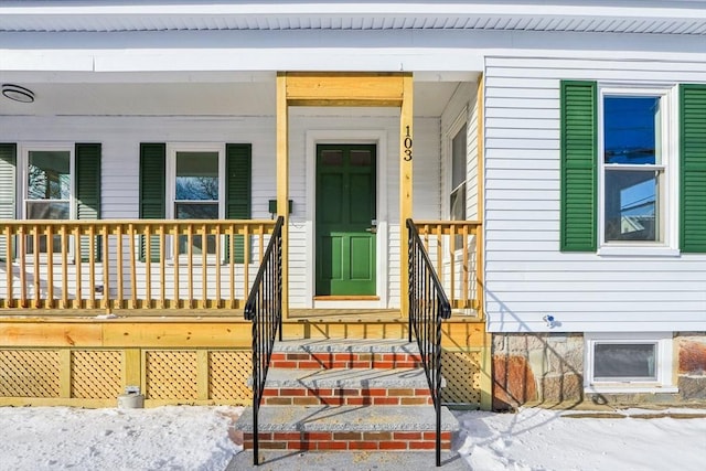 snow covered property entrance featuring covered porch