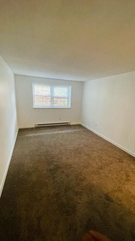 unfurnished room featuring a baseboard heating unit, dark colored carpet, and baseboards