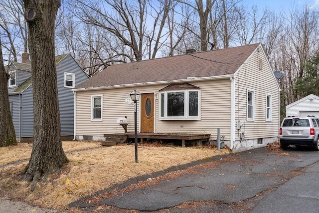 view of front facade with an outdoor structure, roof with shingles, and aphalt driveway