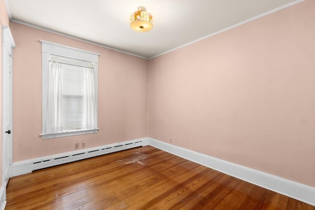 spare room featuring a baseboard heating unit, wood-type flooring, and ornamental molding