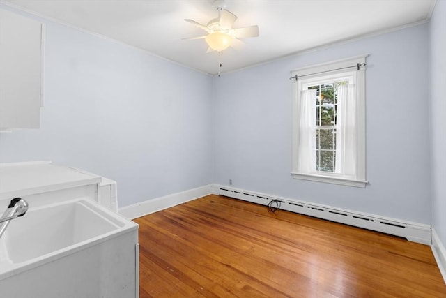 empty room featuring ceiling fan, a baseboard radiator, and sink