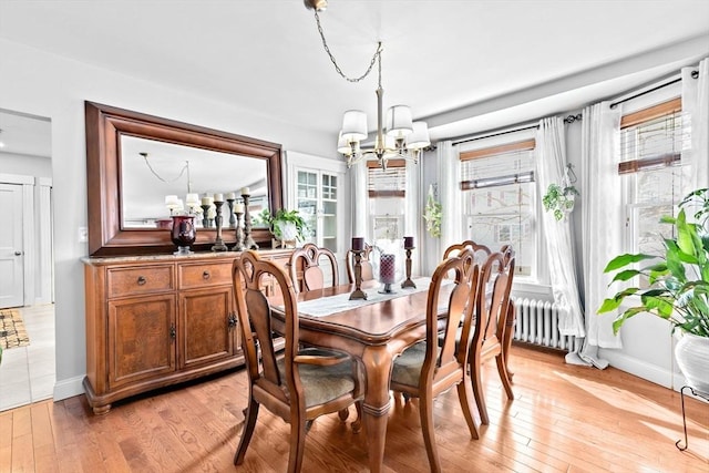 dining room featuring radiator heating unit, an inviting chandelier, plenty of natural light, and light wood-style flooring