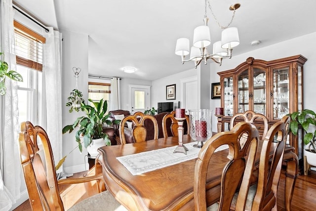 dining space featuring a healthy amount of sunlight, a chandelier, and wood finished floors