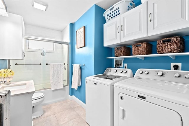 washroom featuring light tile patterned floors, washing machine and dryer, a sink, laundry area, and baseboards