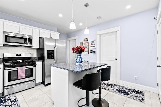 kitchen featuring tasteful backsplash, dark stone counters, a breakfast bar, a center island, and stainless steel appliances