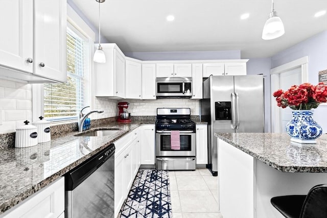 kitchen with appliances with stainless steel finishes, a sink, white cabinetry, and decorative backsplash