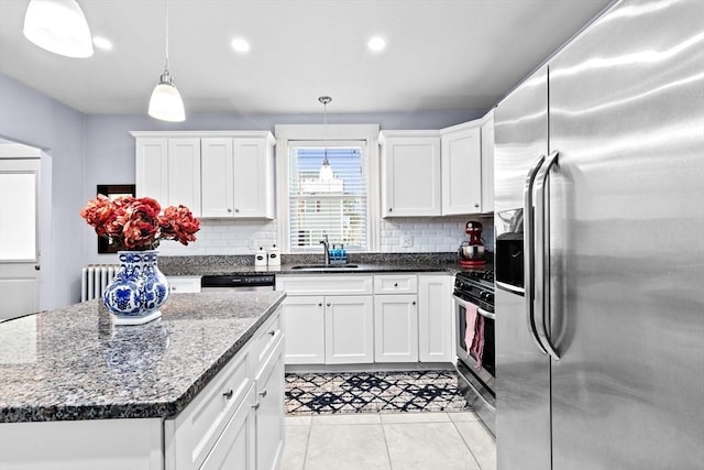 kitchen featuring stainless steel appliances, radiator heating unit, decorative backsplash, white cabinetry, and a sink