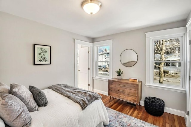 bedroom with multiple windows, baseboards, and wood finished floors