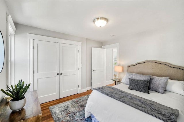 bedroom with a closet, baseboards, and wood finished floors