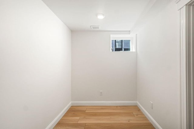 empty room featuring light wood-type flooring, visible vents, and baseboards