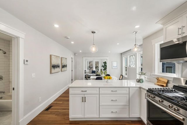 kitchen with visible vents, appliances with stainless steel finishes, decorative light fixtures, a peninsula, and light countertops