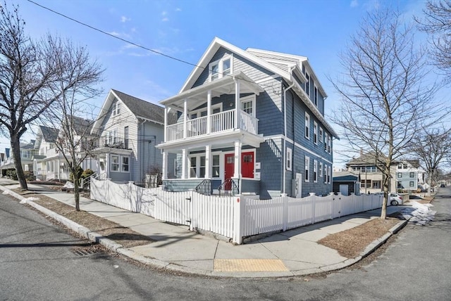 view of front of house with a fenced front yard, a residential view, a porch, and a balcony