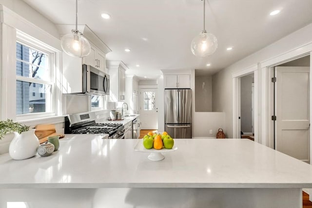 kitchen with stainless steel appliances, plenty of natural light, light countertops, and a sink