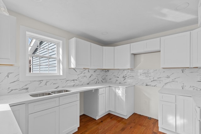 kitchen with hardwood / wood-style flooring, white cabinetry, tasteful backsplash, and sink