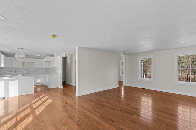 unfurnished living room with a textured ceiling and light hardwood / wood-style floors