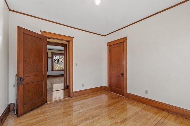 spare room featuring baseboards, light wood finished floors, and crown molding