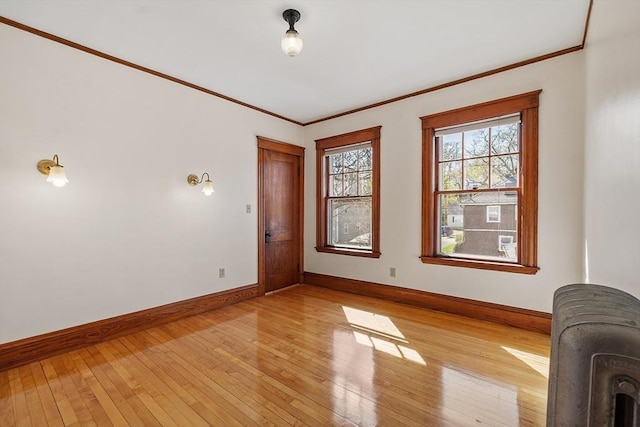 unfurnished room featuring baseboards, light wood-style floors, and crown molding