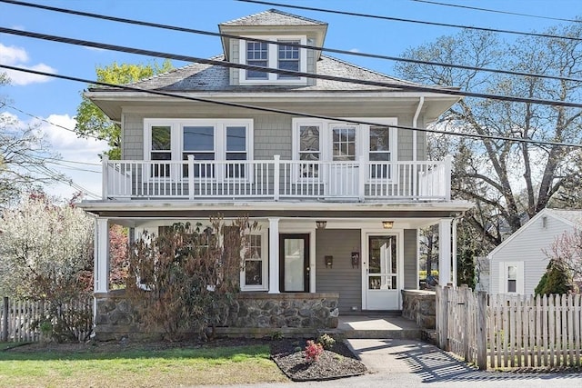 view of front of home featuring a porch, fence, and a balcony