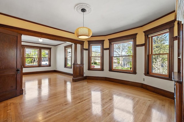 unfurnished room featuring baseboards, ornamental molding, and light wood-style floors