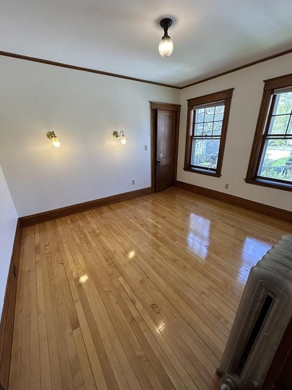 interior space featuring baseboards, ornamental molding, and light wood-type flooring