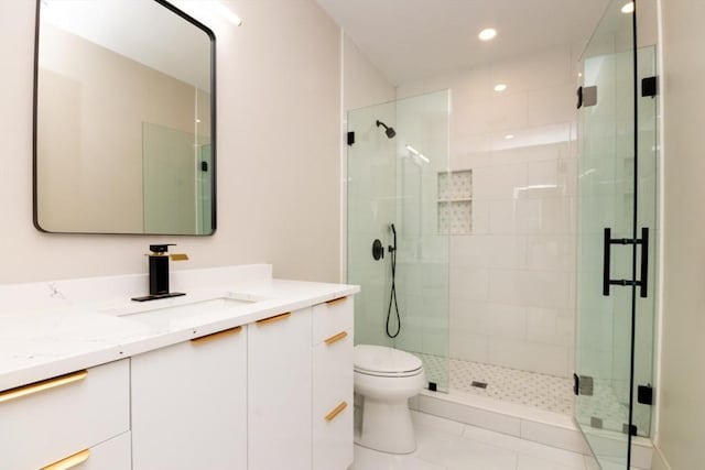 bathroom featuring tile patterned floors, vanity, a shower with shower door, and toilet