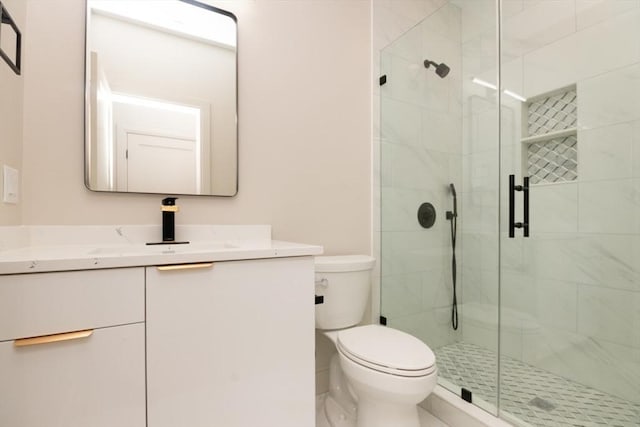 bathroom featuring vanity, toilet, and a shower with door