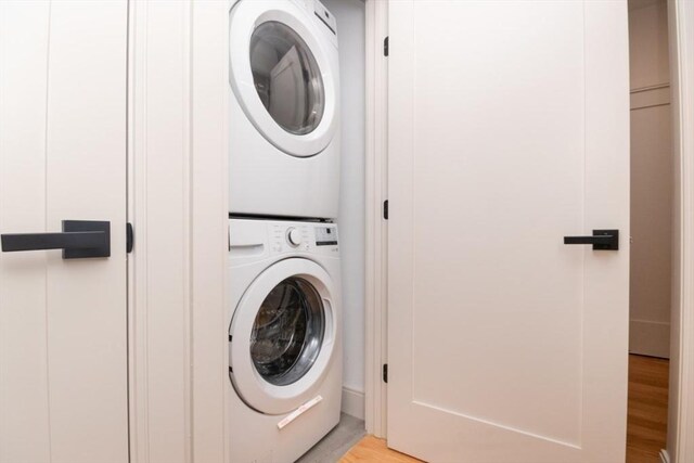 clothes washing area featuring light hardwood / wood-style flooring and stacked washer / dryer