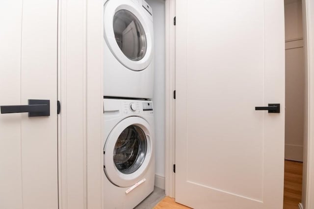 clothes washing area with light hardwood / wood-style flooring and stacked washer / dryer