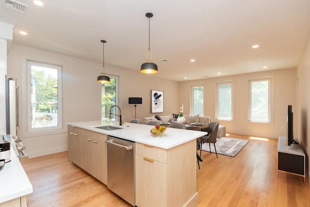 kitchen with sink, an island with sink, stainless steel dishwasher, and light hardwood / wood-style floors