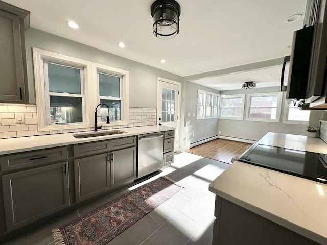 kitchen featuring backsplash, stainless steel dishwasher, dark tile patterned floors, baseboard heating, and sink