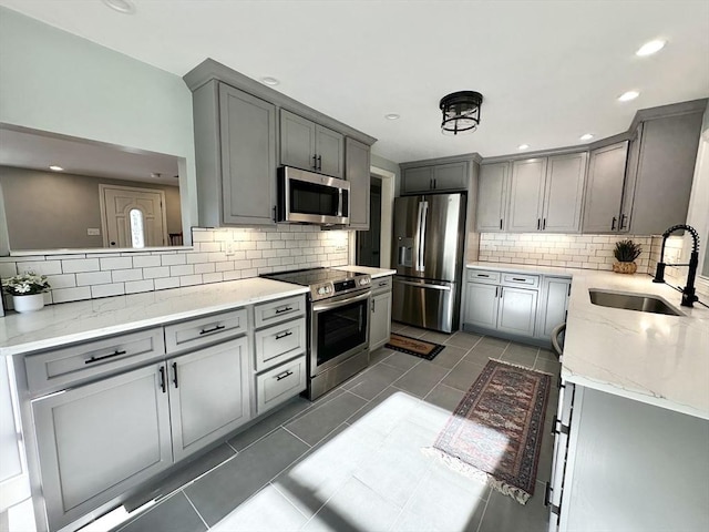 kitchen with stainless steel appliances, tasteful backsplash, gray cabinetry, and sink