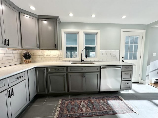 kitchen featuring gray cabinetry, dishwasher, backsplash, sink, and dark tile patterned floors