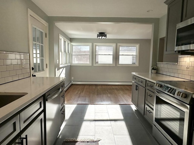 kitchen with appliances with stainless steel finishes, backsplash, and gray cabinets