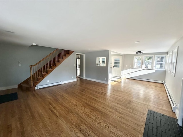 unfurnished living room featuring hardwood / wood-style flooring and a baseboard heating unit