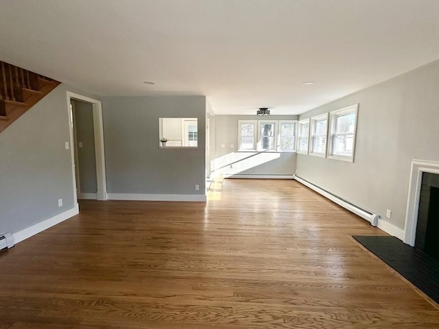 unfurnished living room featuring wood-type flooring, french doors, and a baseboard heating unit