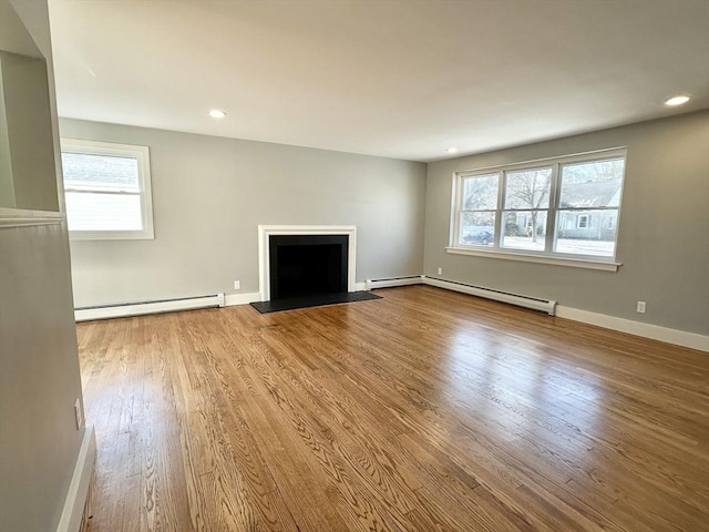 unfurnished living room featuring light hardwood / wood-style flooring, a wealth of natural light, and a baseboard radiator