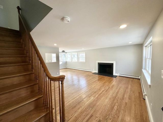 unfurnished living room featuring light wood-type flooring and baseboard heating