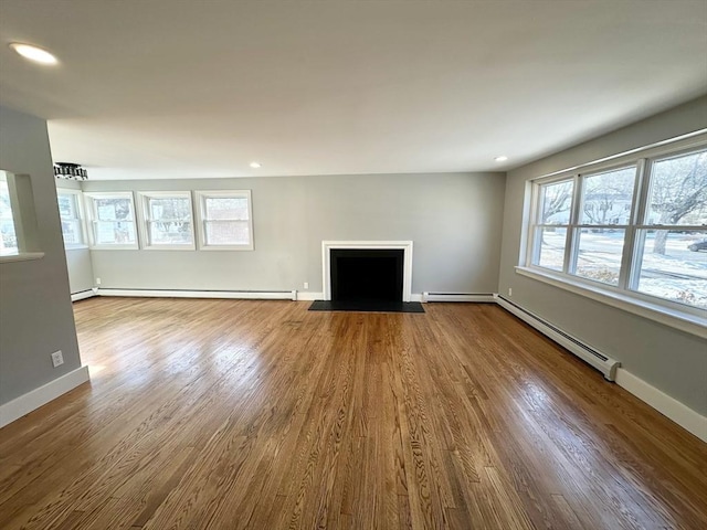 unfurnished living room featuring hardwood / wood-style flooring and a baseboard heating unit