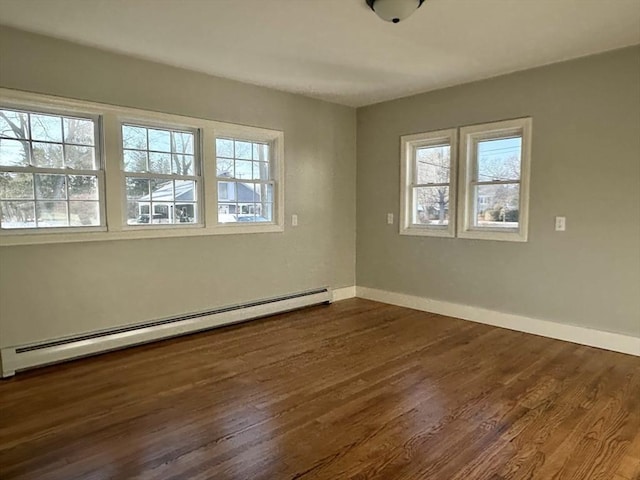 empty room with dark hardwood / wood-style flooring, plenty of natural light, and baseboard heating