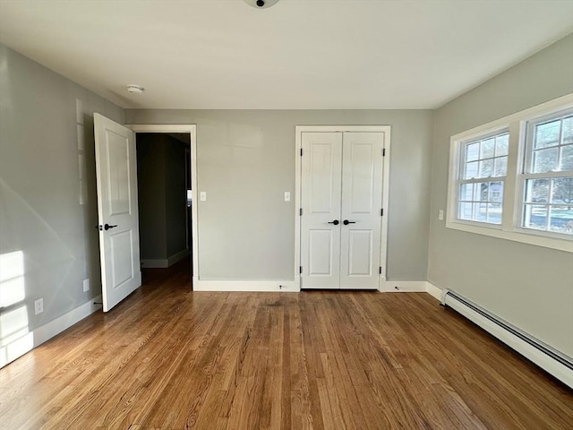 unfurnished bedroom featuring a baseboard radiator, light hardwood / wood-style flooring, and a closet