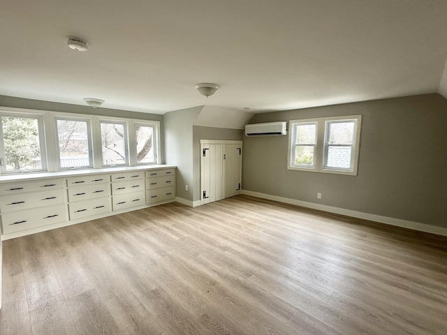 bonus room featuring lofted ceiling, light hardwood / wood-style floors, and an AC wall unit