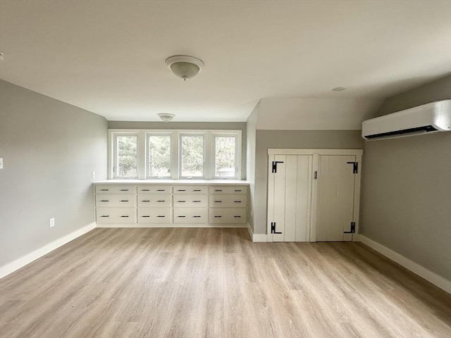 bonus room featuring an AC wall unit, light hardwood / wood-style flooring, and lofted ceiling