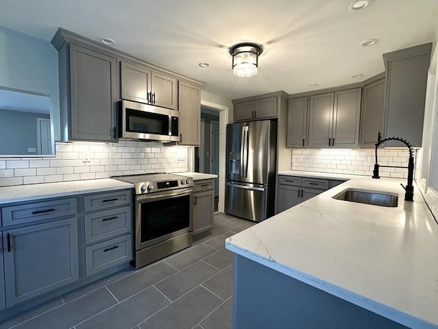 kitchen with appliances with stainless steel finishes, backsplash, dark tile patterned floors, and sink