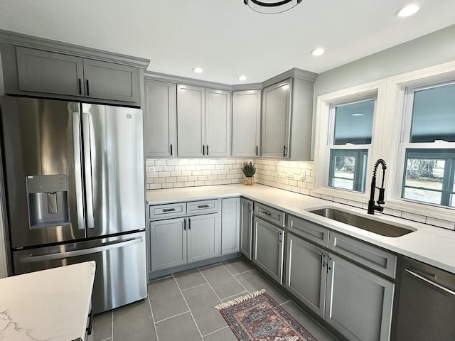 kitchen with sink, dark tile patterned floors, stainless steel refrigerator with ice dispenser, gray cabinets, and decorative backsplash