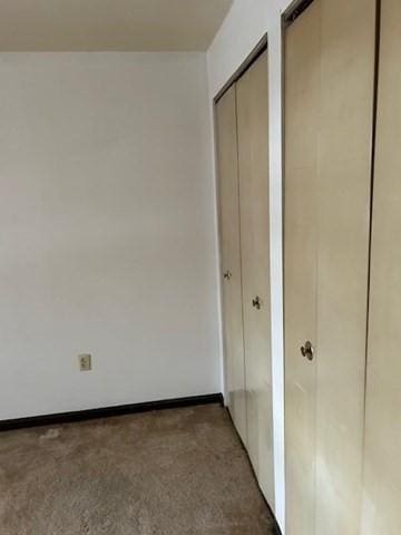 unfurnished bedroom with baseboards and multiple closets