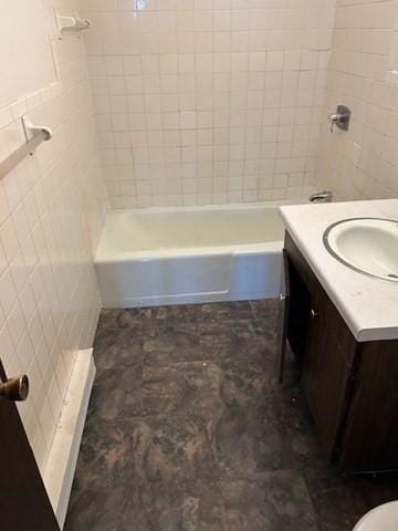 bathroom featuring vanity, bathtub / shower combination, and tile walls