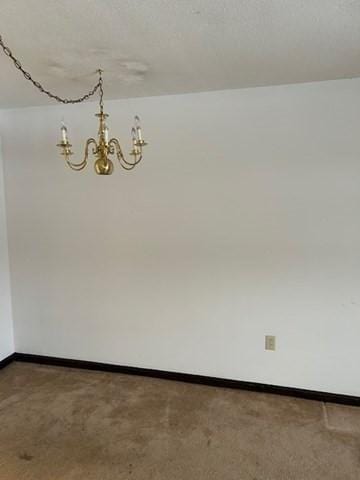 unfurnished room featuring a chandelier and baseboards