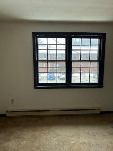 carpeted spare room featuring baseboard heating