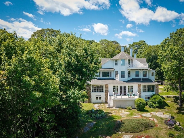15 Brier Rd, Gloucester, MA 01930 - back of property featuring a balcony, a chimney, stone siding, a yard, and a view of trees