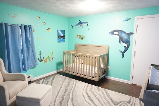 bedroom with a nursery area, a textured ceiling, dark hardwood / wood-style floors, and a baseboard heating unit